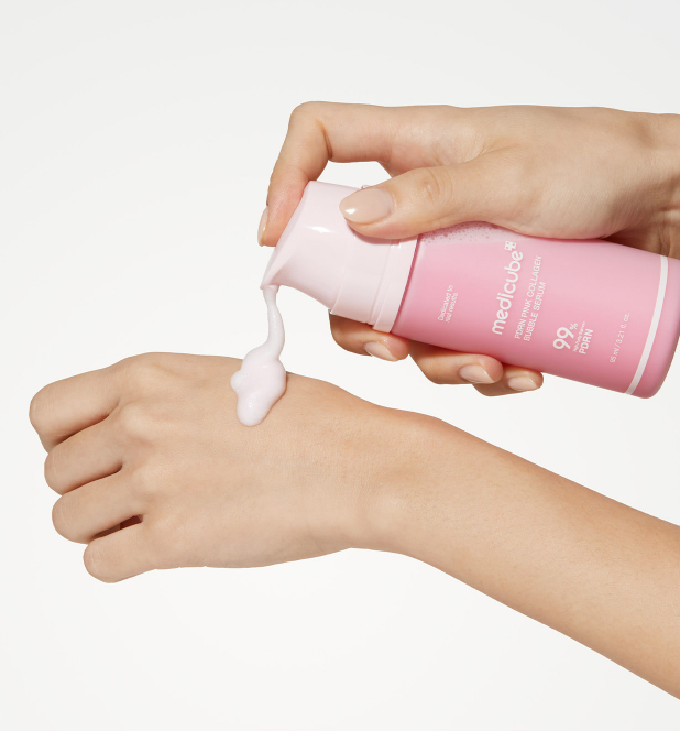 AgelessBeauty3000.com medicube | PDRN Pink Collagen Bubble Serum Hand applying pink cream from a bottle labeled 'Medichreme' to another hand on a white background