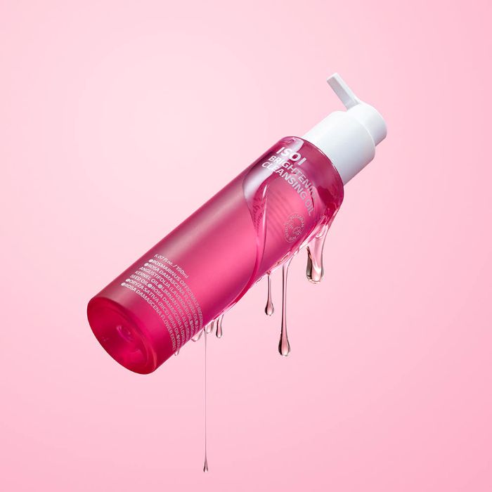 AgelessBeauty3000.com isoi | Brightening Cleansing Oil Pink skincare bottle with droplets on a pink background