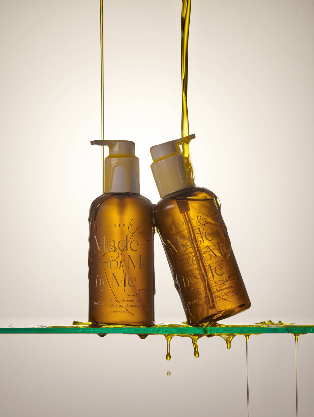 AgelessBeauty3000.com  AXIS-Y  |  Biome Resetting Moringa Cleansing Oil  Two bottles of 'Made by Me' product with a beige background