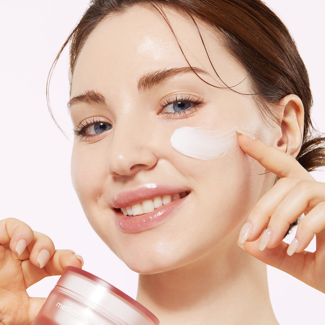 AgelessBeauty3000.com  medicube | Triple Collagen Cream   Woman applying cream to her face with a pink jar in the foreground