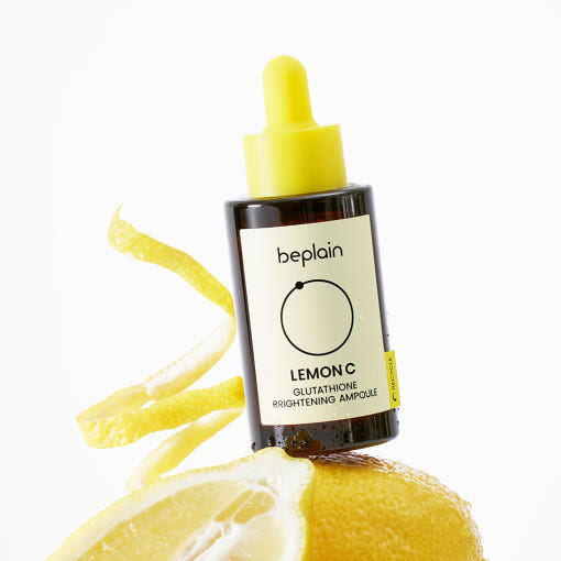 ThatKBeautyShop.com  beplain | Lemon C Glutathione Brightening Ampoule  A bottle of beplain Lemon C Glutathione Brightening Ampoule serum, styled on top of a fresh lemon slice with curled lemon peels against a clean white background.