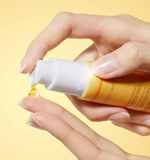 AgelessBeauty3000.com medicube | Kojic Acid Turmeric Vita Eye Gel SerumHand holding a bottle of skincare product with a yellow background