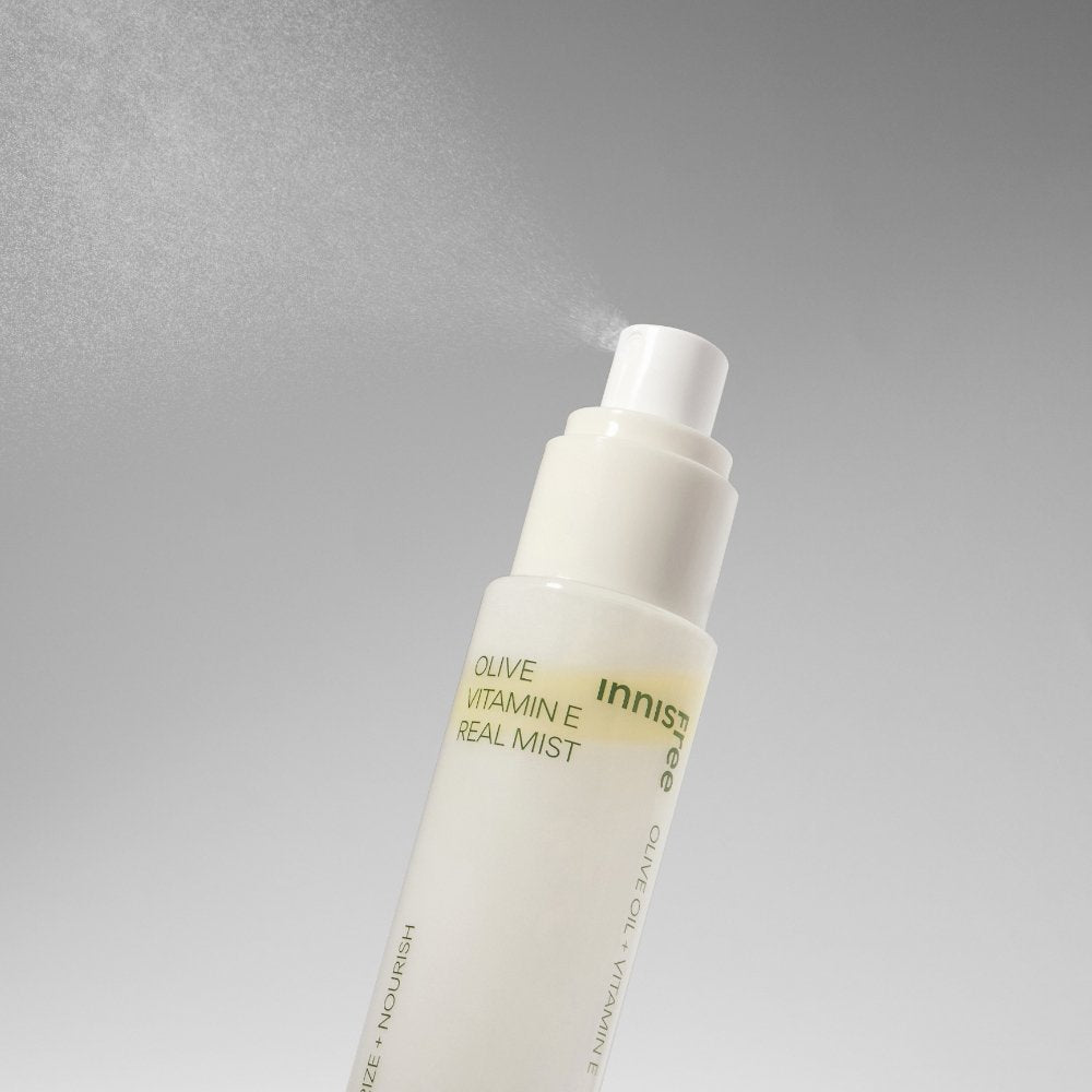 ThatKBeautyShop.com  innisfree | Olive Vitamin E Real Mist    Innisfree Olive Vitamin E Real Mist spray bottle with a white pump dispenser, shown spraying with fine mist against a gray gradient background.